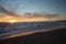 Orange sunset over ocean with calm water and sandy beach