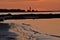 Orange sunset reflected in bay and beach of rising tide