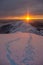 An orange sunset shines on the trails leading to the top of a snow-capped mountain. alpine view, Carpathians, Marmaros