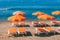 Orange sunshades and deckchairs against ocean