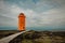 Orange SvÃ¶rtuloft Lighthouse on western part of Iceland on a colorful picturesque backdrop of clouds, lava fields and moss