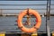 An orange swimming ring on a metal fence on a pedestrian crossing at a wharf beside the river
