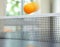 Orange table tennis ball moving over net