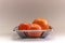 Orange tangerine basket in a plain grey background