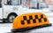 Orange taxi sign on a car roof on a blurred bus background.