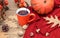 Orange tea mug with a teaspoon on the background of ripe pumpkins and a bouquet of physalis, oak leaves, cones, acorns on a