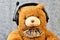 Orange teddy bear listening music in headphones