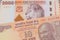 A orange ten rupee bill from India paired with a orange and white 2000 shilling bill from Tanzania.