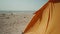 orange tent on sea beach at sunny summer morning. wind blows and tent shakes, traveling with tents