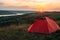 Orange tent at sunset in the mountains. Camping in nature