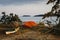 Orange tent, yellow kayak on the island. Sunset, evening time. Kayaking, camping equipment, outdoor activities
