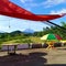 orange tents and colorful umbrellas with river, hills and Kerinci mountain in the background