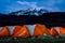 Orange tents illuminated before Mount Kilimanjaro during night