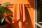 An orange terry towel is hanging on a hanger