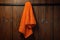 An orange terry towel is hanging on a hanger