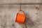 Orange tin cup hanging on stainless rail on cement wall background