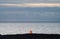 Orange tiny lighthouse facing the huge ocean