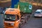 Orange truck drops off a trash compactor in the yard of a hospital