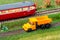 Orange truck on model train layout next to historic passenger train
