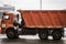 Orange truck is running on the street in city. Recycling truck rides on the winter road