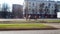 Orange-uniformed janitors sweeping the lawn along a road on a city street. Sunny spring day. The work of the municipal