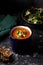 Orange vegetable cream soup in mug (tomato, carrot, lentil, pumpkin), delicious hot homemade lunch in cup. Dark background