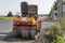 Orange Vibration roller compactor standing on a ground near asphalts road at road construction and repairing asphalt