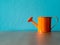 Orange watering cans put on wooden table. the background is turquoise and copy space for content