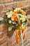 Orange wedding bouquet on a brick background