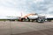 An orange and white Easyjet on the tarmac boarding passengers via a multilevel boarding ramp on an overcast day