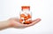 orange and white medicine supplement pill capsules with hand bottle and clear background