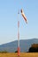 An Orange Windsock or Windvane on a Red and White Pole