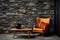 Orange wingback lounge chair and wooden coffee table against wild stone cladding wall