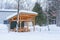 Orange wooden garden pavillion in winter with white snow