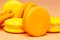 Orange and yellow macarons or macaroons stacked over pinky orange background