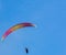 Orange and yellow paraglider on clear blue sky