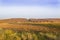 Orange-yellow plowed field against the backdrop of an autumn forest with a freeway in the middle