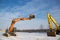 Orange and yellow powerful crawler excavators standing at a construction site on snowy ground on a sunny winter day