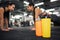 Orange and yellow water bottles stand in front of picture. Asian and european women stand in plank pose behind. They