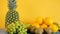 Oranges, bananas, pineapple, kiwi and grapes on yellow background