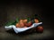 Oranges with leaves in basket, dark ciaroscuro style still life. Fruit on hessian .