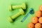 Oranges near dumbbells, cyan measuring tape on green background,