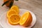 Oranges and Orange Slices on white plate with leafs on white marble