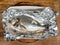 Orata fish baked in foil on old wooden table