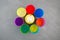 Orbeez toy. Multicolored Hydrogel balls or Water beads in plastic cups on grey background, top view. Flexible gel balls for