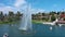 orbit aerial footage of rippling green water of Echo Park Lake with people in pedal boats, a water fountain, green trees and grass