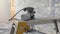 An orbital sander resting on a metal workbench in a dusty room being stripped