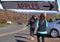 An orchard apple sign swinging with the wind as customers head home