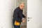 Ordinary elderly man independently repairs a door
