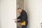 Ordinary elderly man independently repairs a door